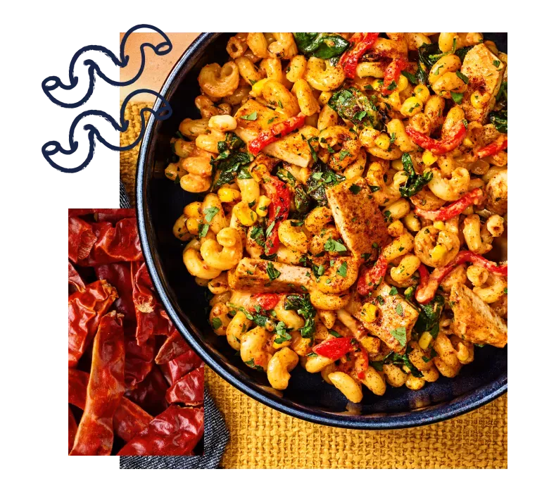 Bowl of chipotle chicken cavatappi on a place mat accented with doodles of cavatappi noodles and a photo of chipotle peppers