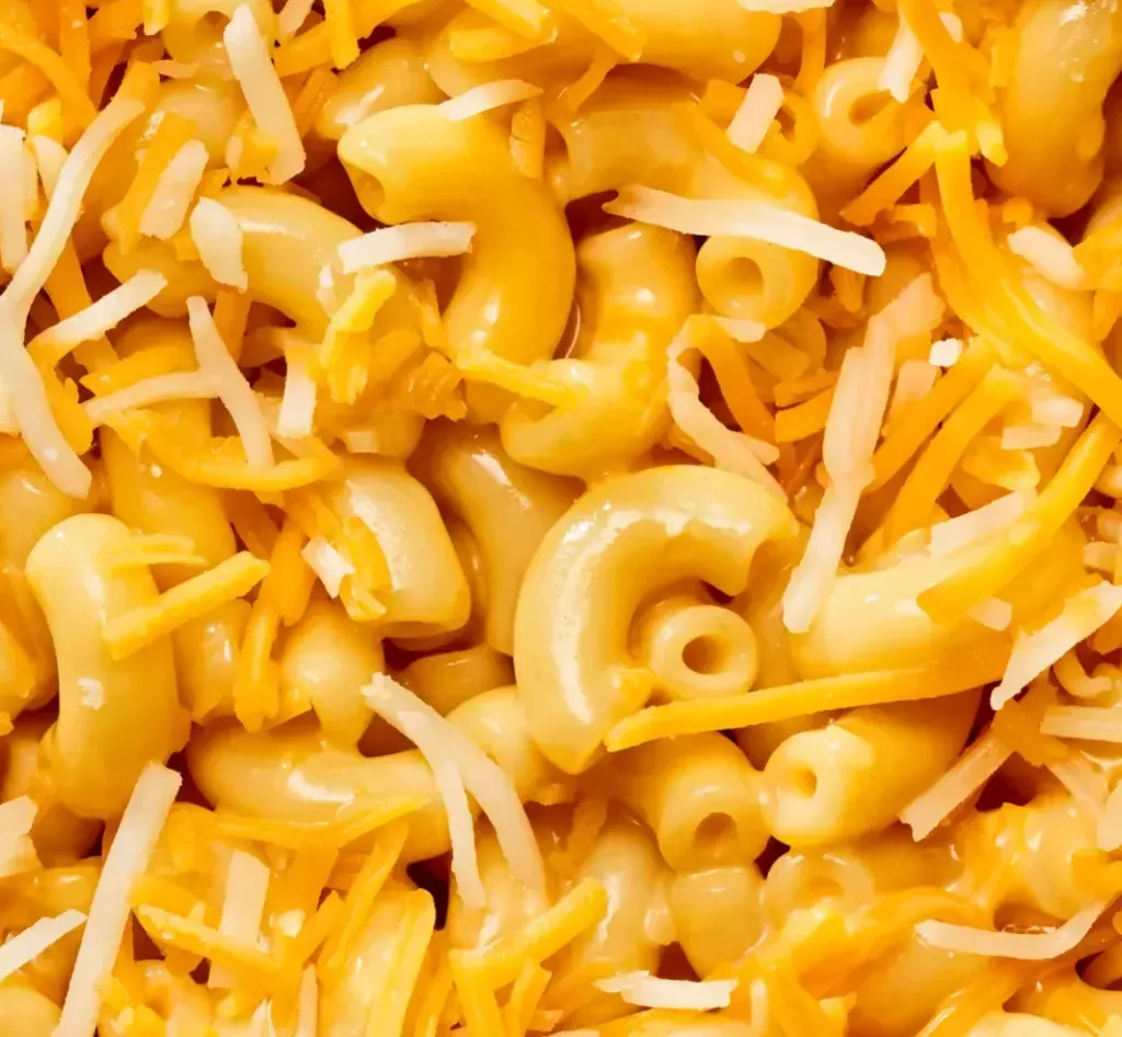 Close up photo of elbow noodles in cheese sauce topped with shredded cheese