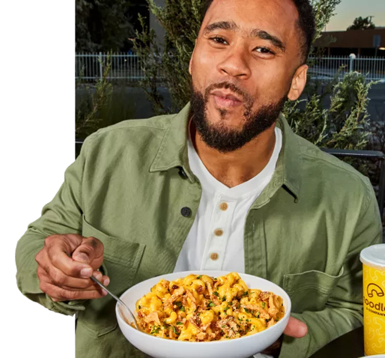 Man in green shirt enjoying a bowl of mac and cheese