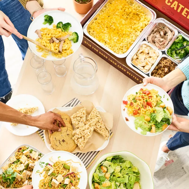 catering table top with an assortment of dishes and desserts and people filling their plates