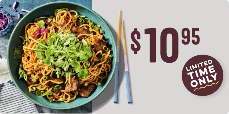 $10.95 limited time only. Spicy Korean Steak Noodles. Shown with green onions on the top, and plated in a green bowl with chopsticks on the side.