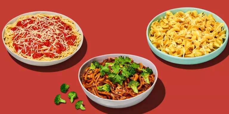 Spaghetti with marinara in a white bowl, Japanese pan noodles in a white bowl with broccoli on the side, buttered noodles in a blue bowl.